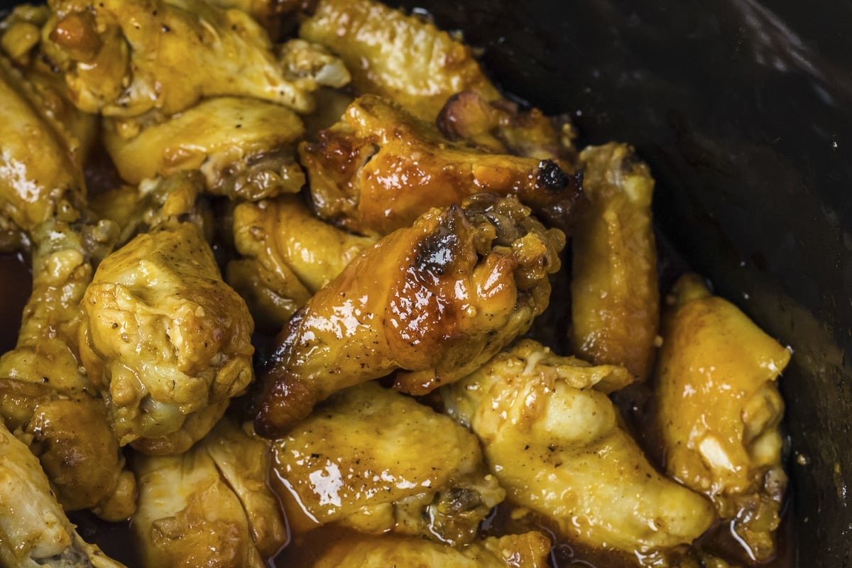 close up of cooked honey mustard wings in slow cooker