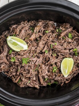 mexican shredded beef in slow cooker with 2 limes on top