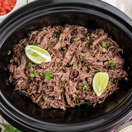 mexican shredded beef in slow cooker with 2 limes on top