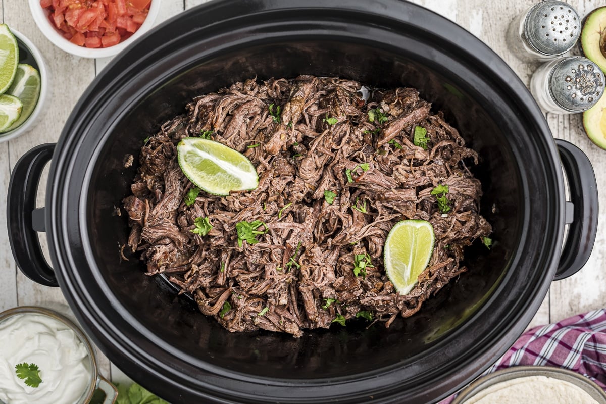 mexican shredded beef in slow cooker with 2 limes on top