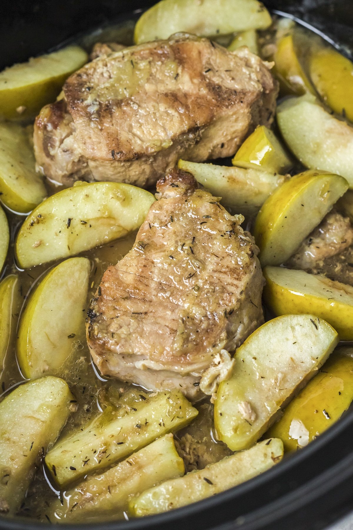 close up of pork chops and apples in crockpot