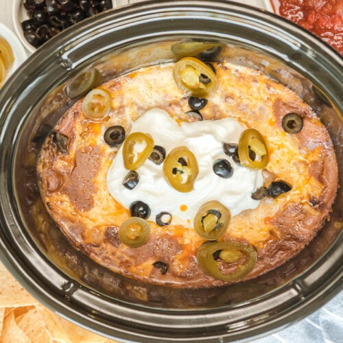 texas trash dip, done cooking in slow cooker with sour cream on top