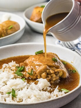 chicken on plate with adobo sauce being poured over