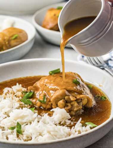 chicken on plate with adobo sauce being poured over