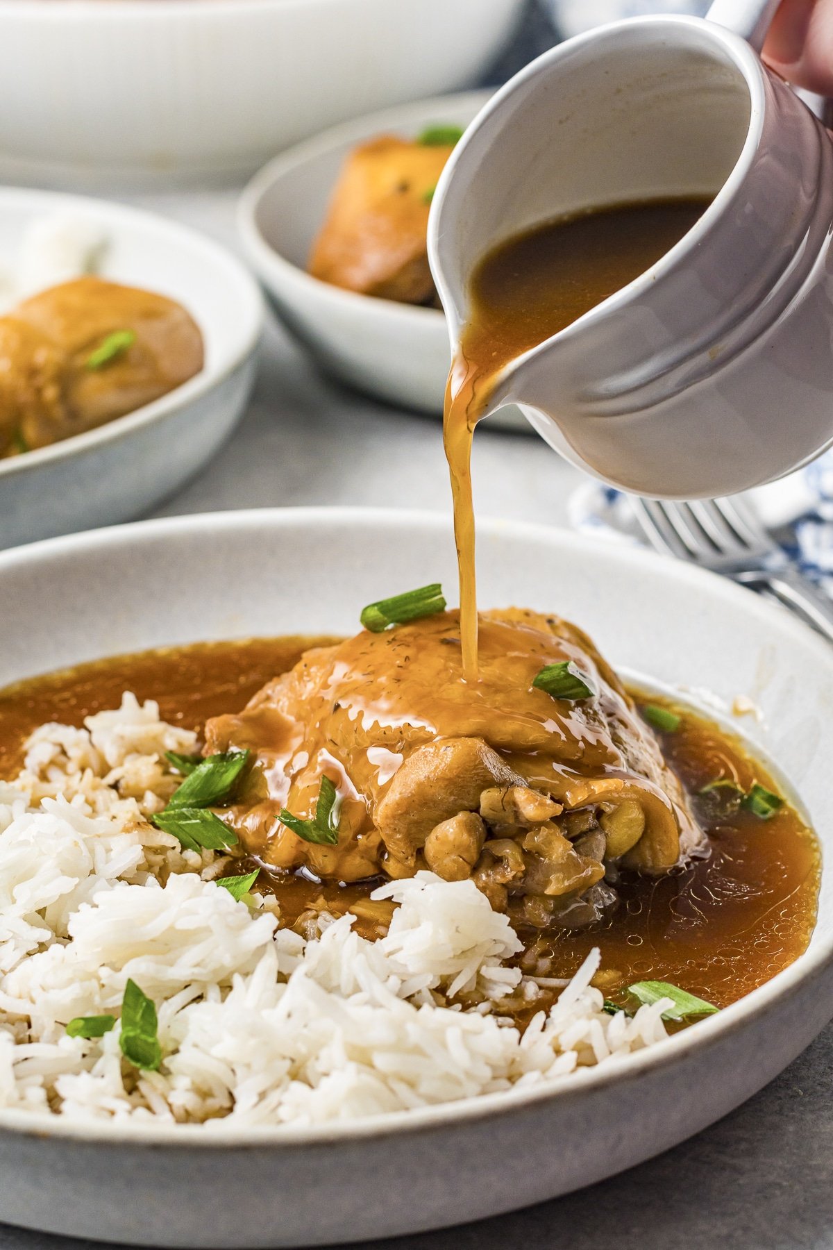 chicken on plate with adobo sauce being poured over