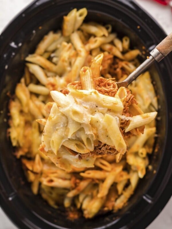 chicken parmesan pasta on a spoon, coming from the slow cooker.