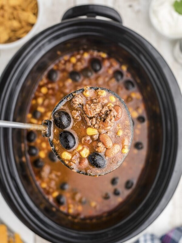 Taco soup in a ladle coming from slow cooker.