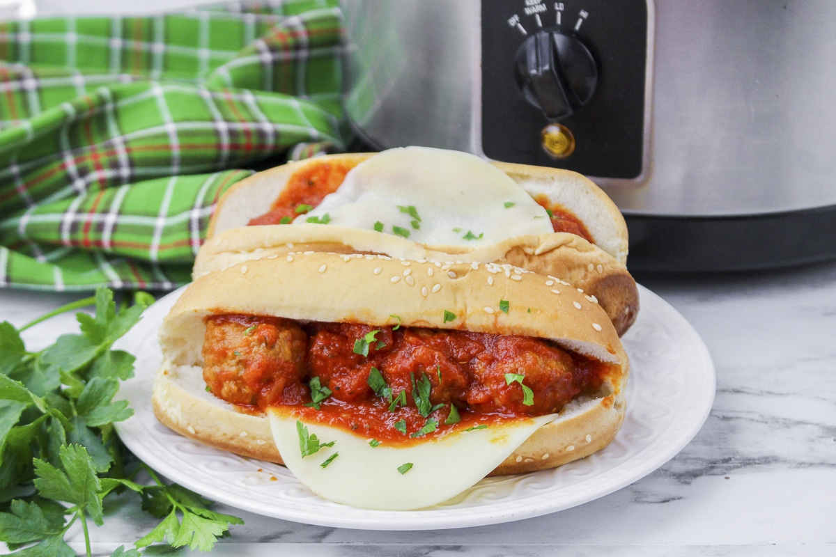 plate of meatballs subs with cheese and parsley.