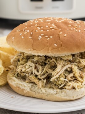 a chicken sandwich on a plate with potato chips.
