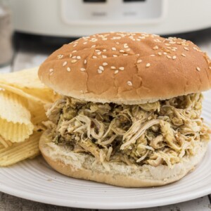a chicken sandwich on a plate with potato chips.