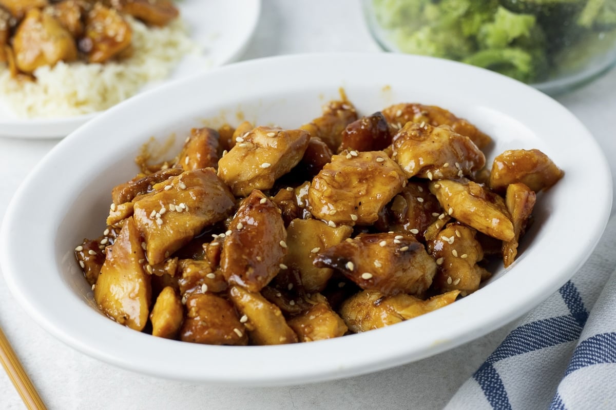 bowl of orange chicken with sesame seeds on top.