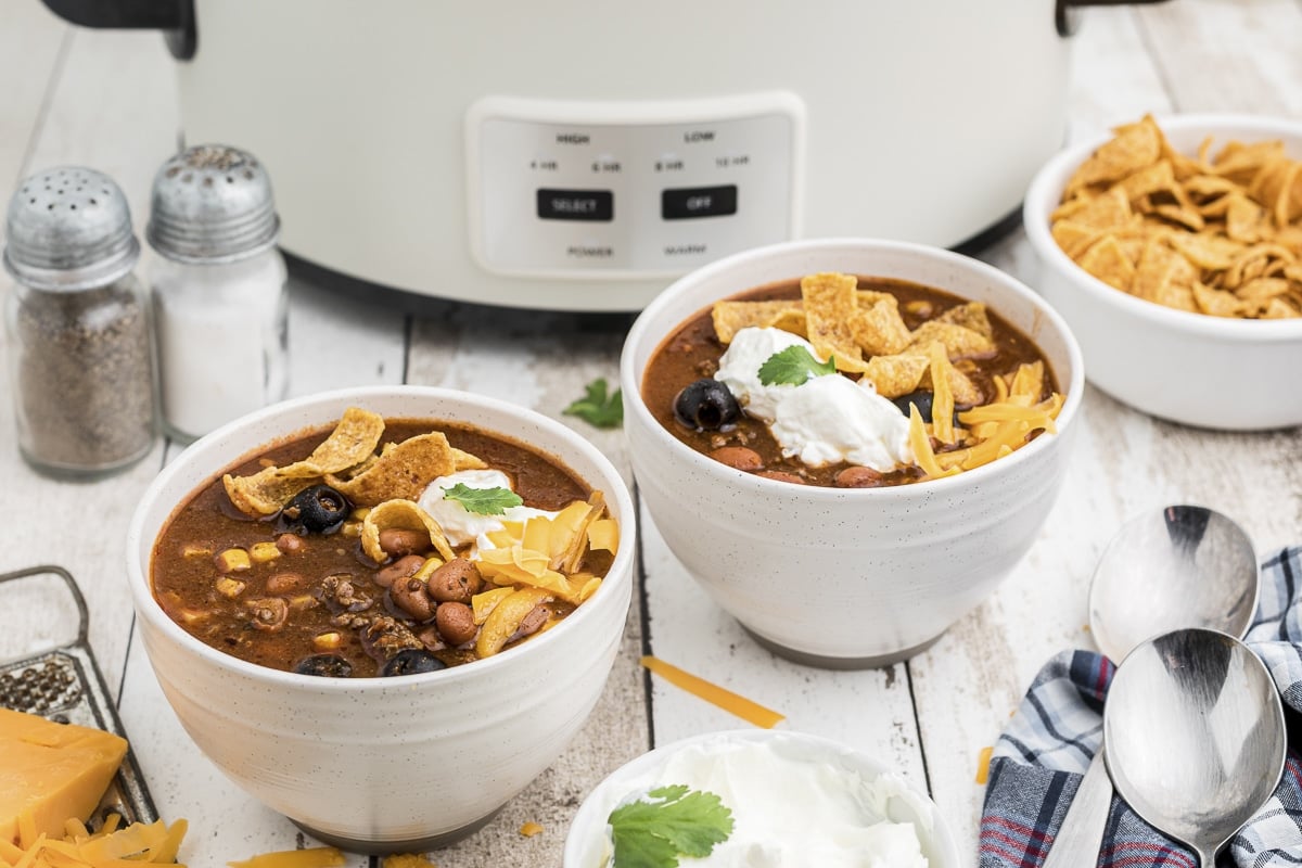 2 bowls of taco soup with cheese, fritos and sour cream