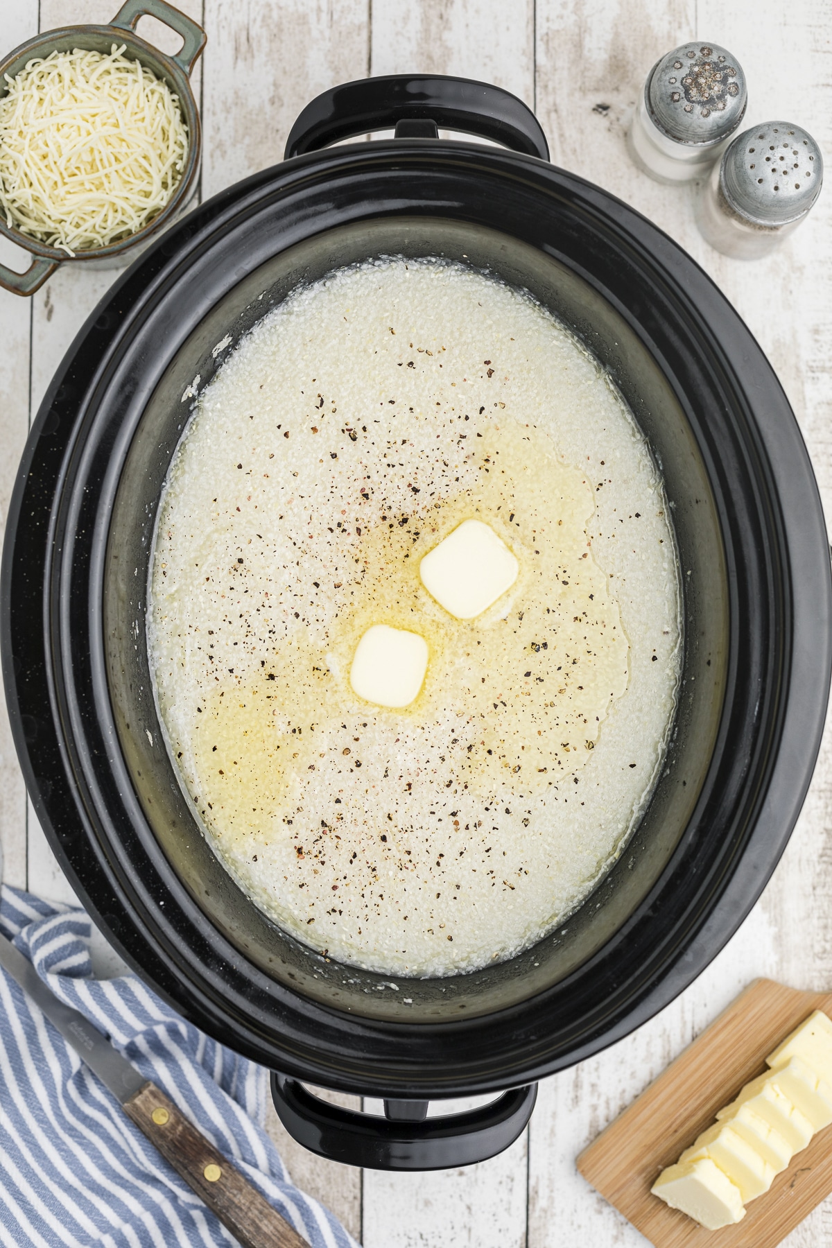 overhead shot of grits with pepper and butter on top.