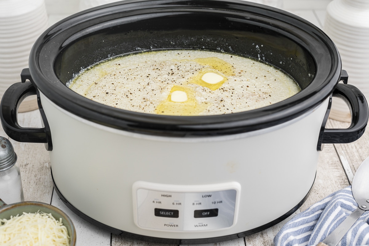 side view of grits in the crockpot with butter on top.