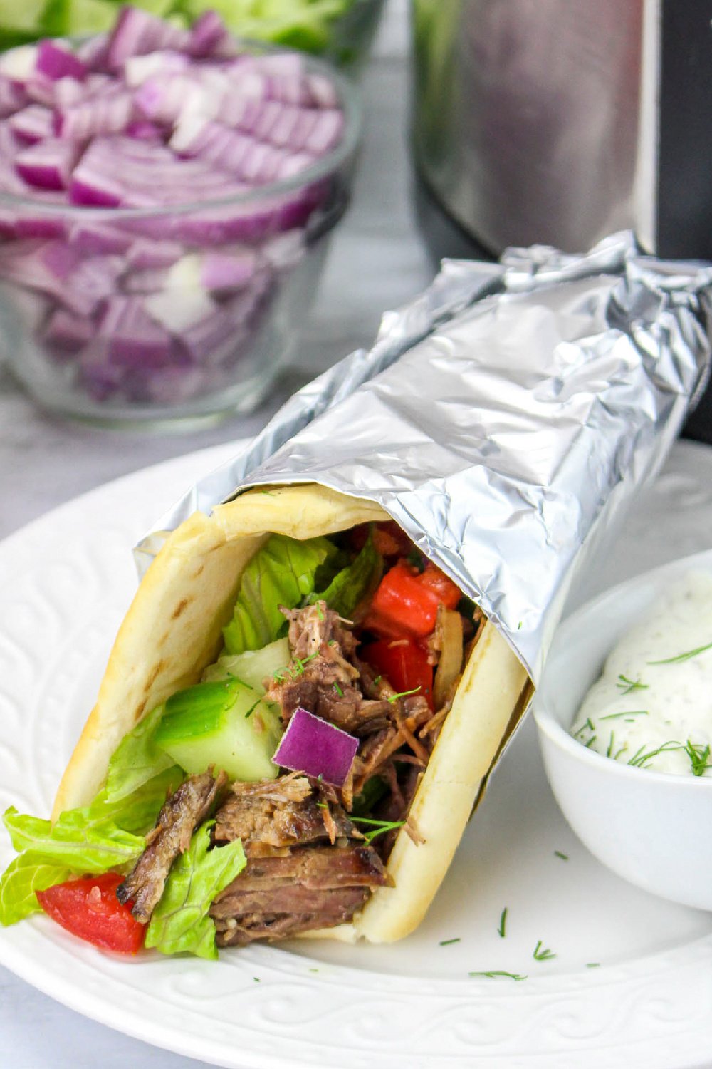 close up image of a beef gyro on a plate.