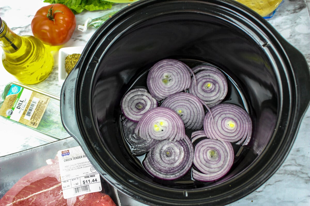 Onions on the bottom of a slow cooker.