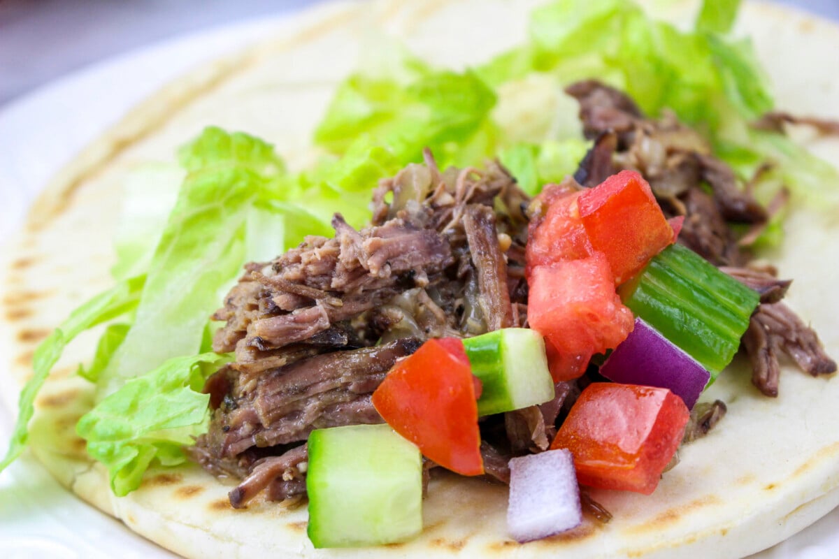 beef gryro with cucumber and tomato on top.