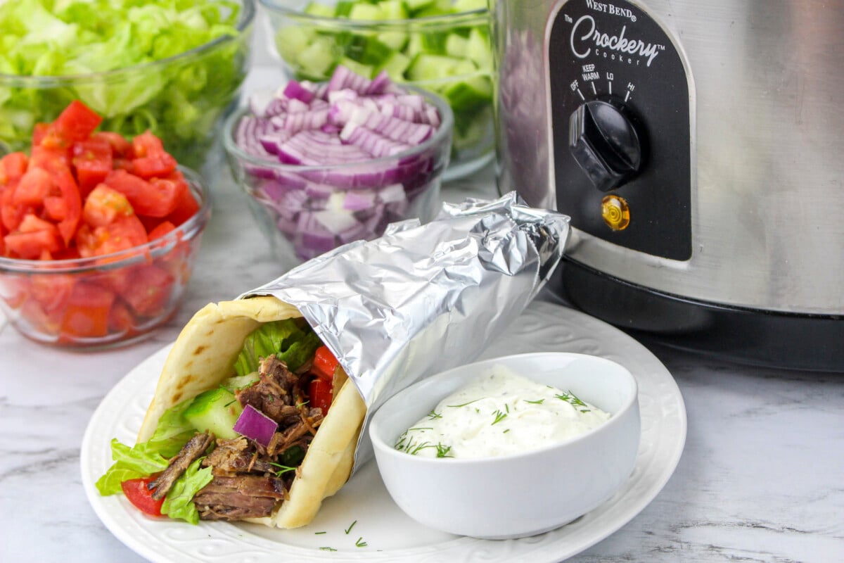 beef gyro wrapped in foil in front of slow cooker.