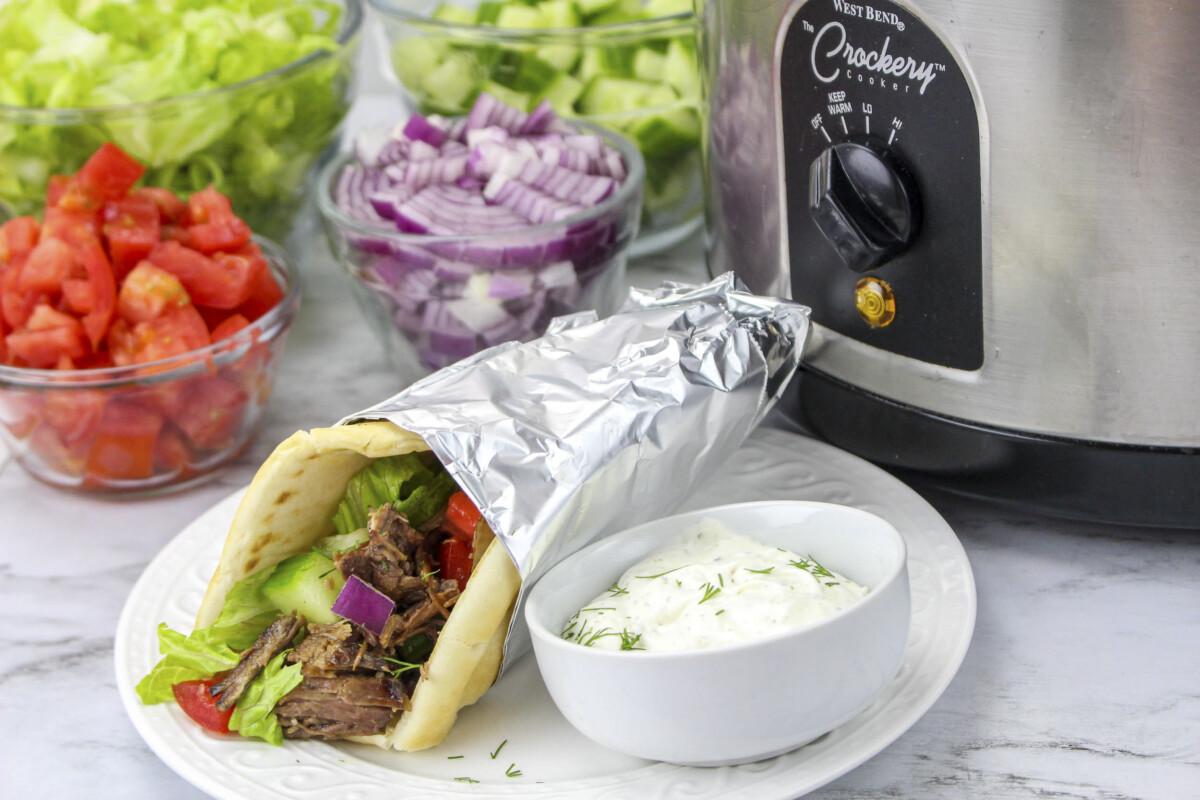 beef gyro wrapped in foil in front of slow cooker.