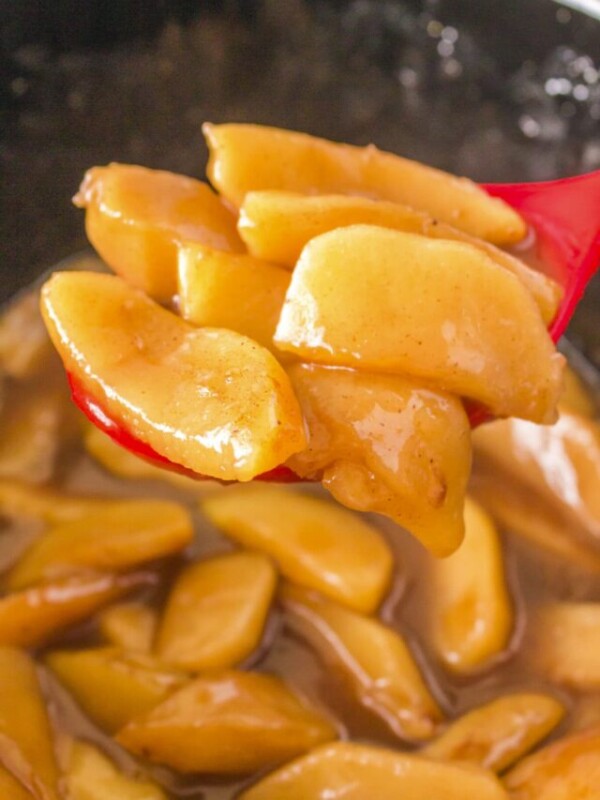 cooked fried apples on a red spoon.
