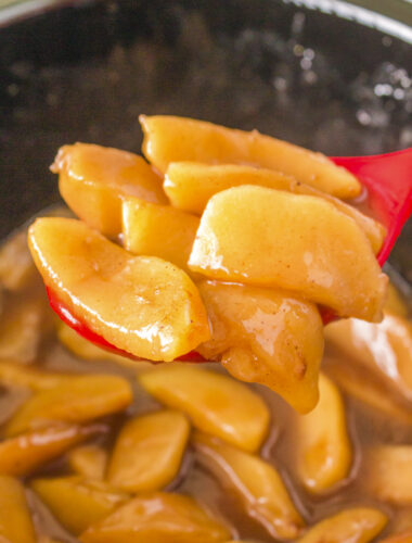 fried apples on a spoon coming from crockpot