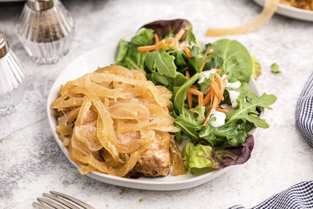 pork chop with onions on plate with salad.