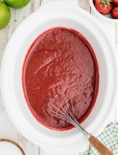 cooked strawberry applesauce with whisk in it.