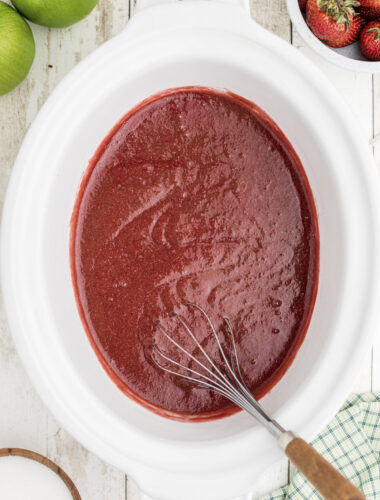 cooked strawberry applesauce with whisk in it.