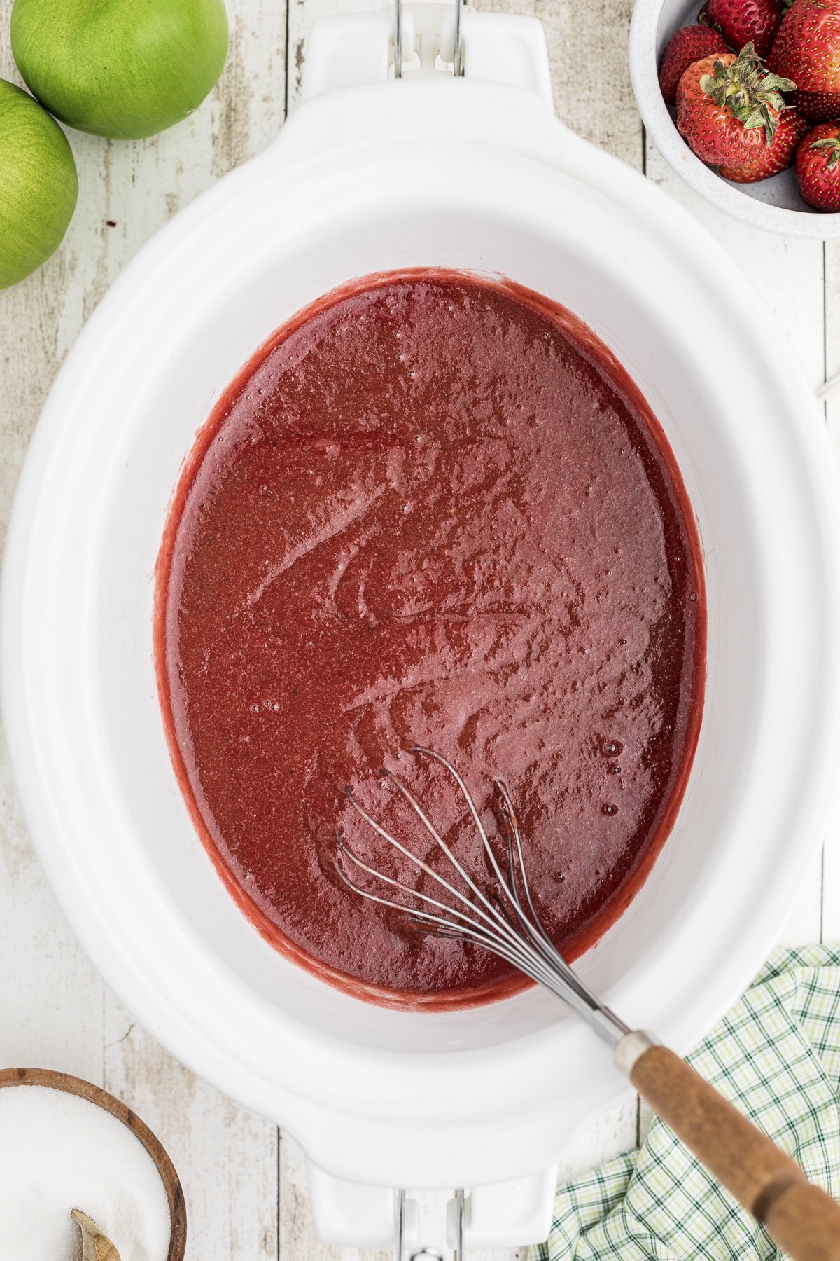 cooked strawberry applesauce with whisk in it.