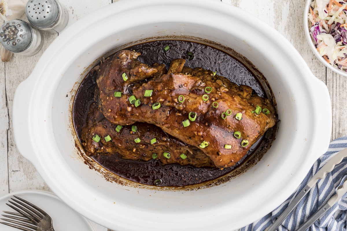 pork ribs with teriyaki sauce and green onions in slow cooker.