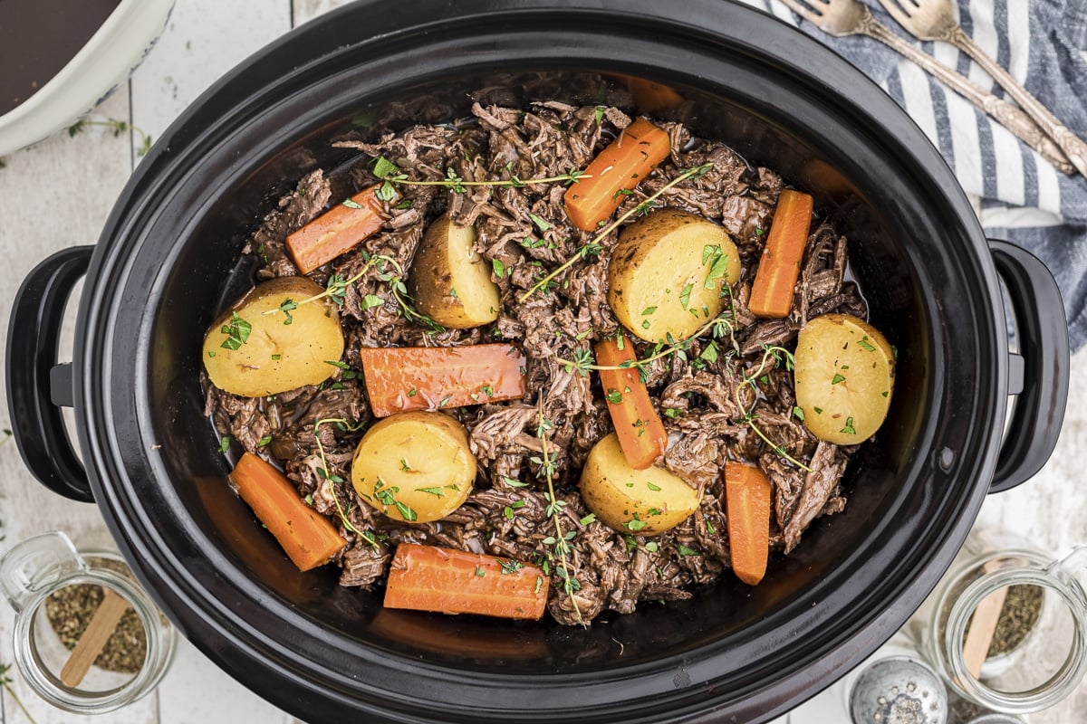 venison pot roast shredded with vegetables in crockpot.