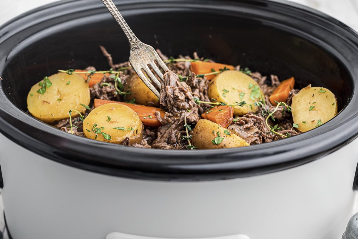 venison pot roast in crockpot and on fork.