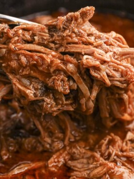 pulled pork with bbq sauce on tongs.