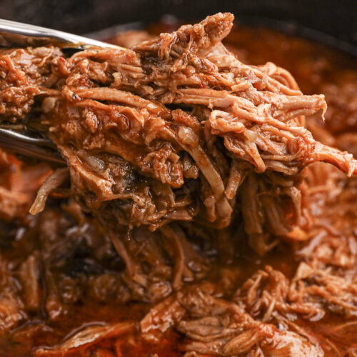 pulled pork with bbq sauce on tongs.