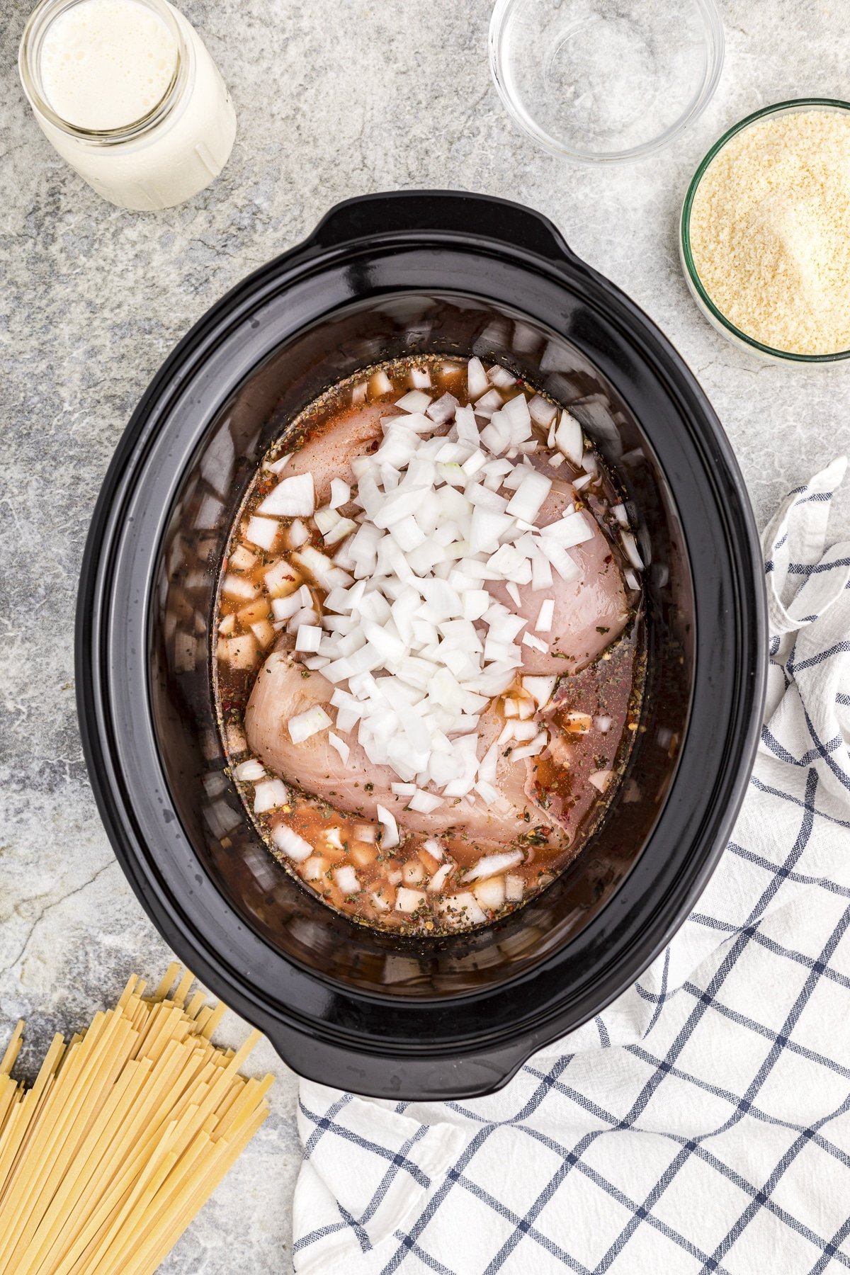 Chicken, broth, onions and seasonings in a slow cooker.