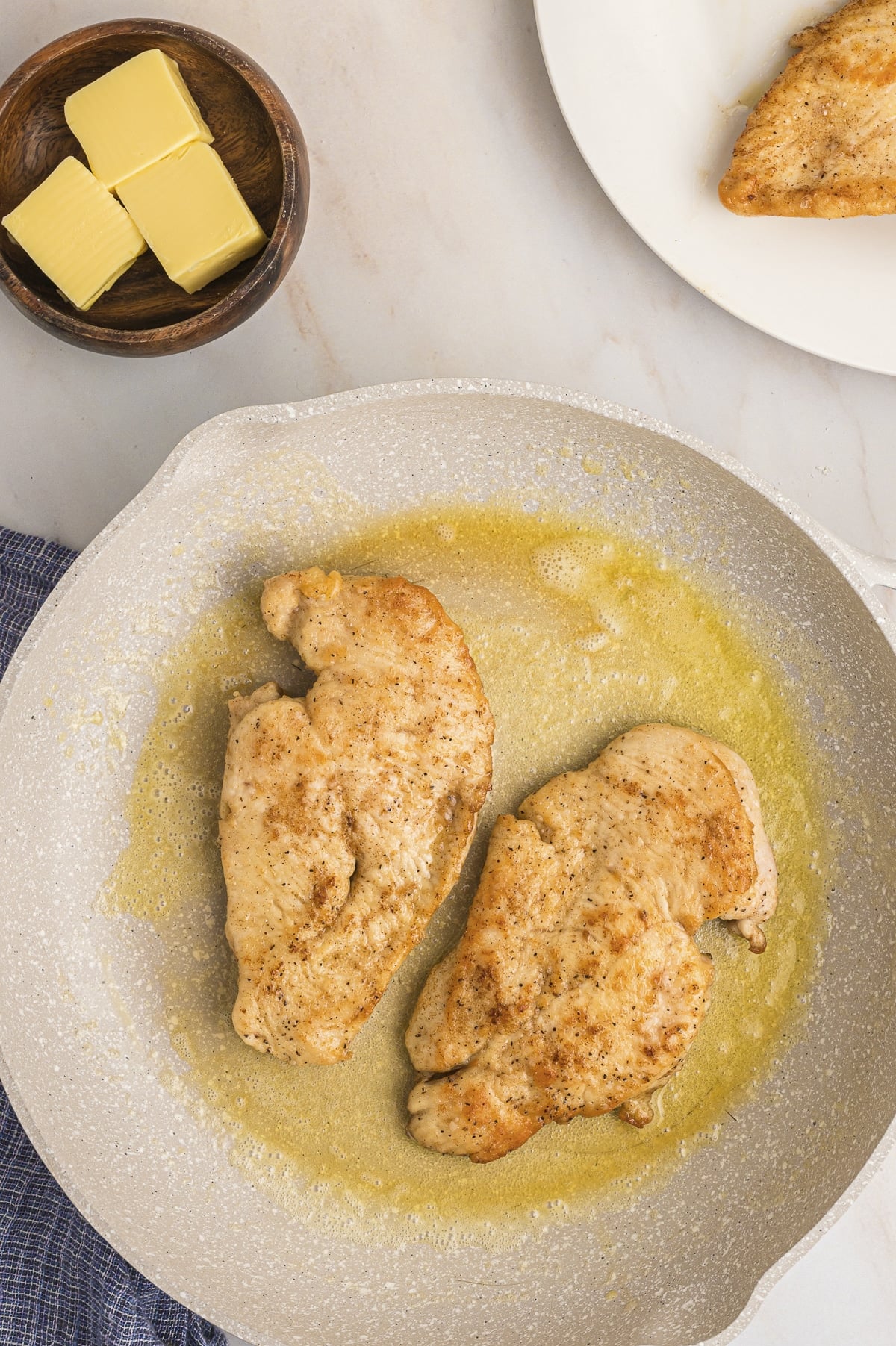 chicken breasts being browned in a pan.