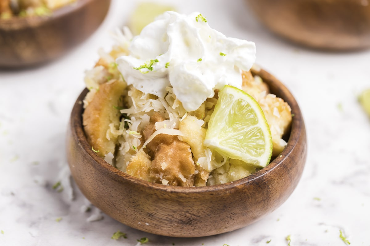 Bowl of coconut bread pudding with lime and whipped cream.