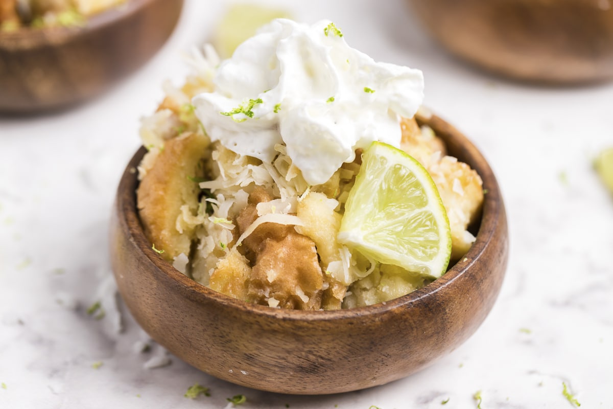 Bowl of coconut bread pudding with lime and whipped cream.