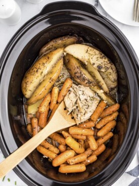 garlic butter chicken in slow cooker on a wooden spoon.