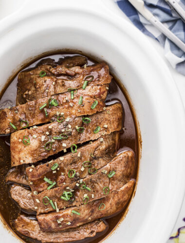 dr. pepper ribs in slow cooker with onion on top.