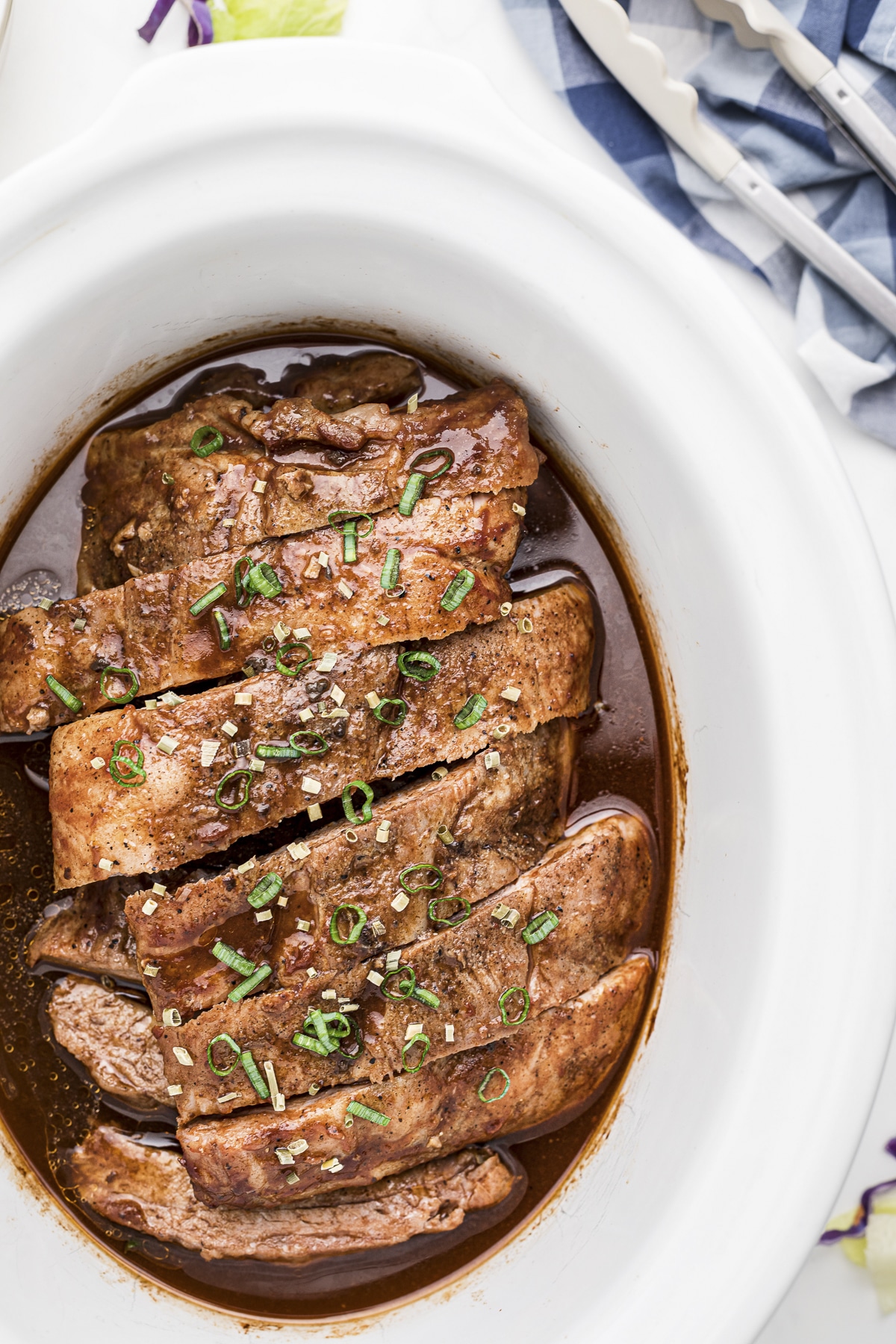 dr. pepper ribs in slow cooker with onion on top.