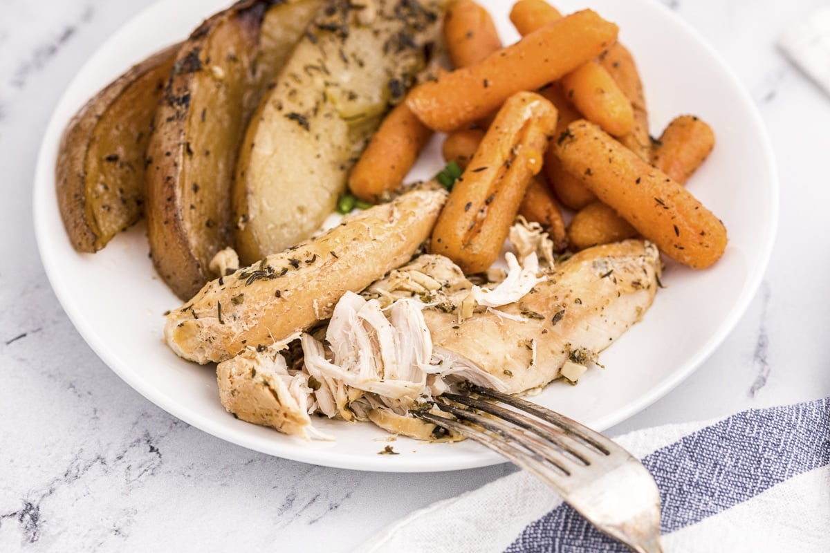 chicken tenderloins on plate with carrots and potatoes.