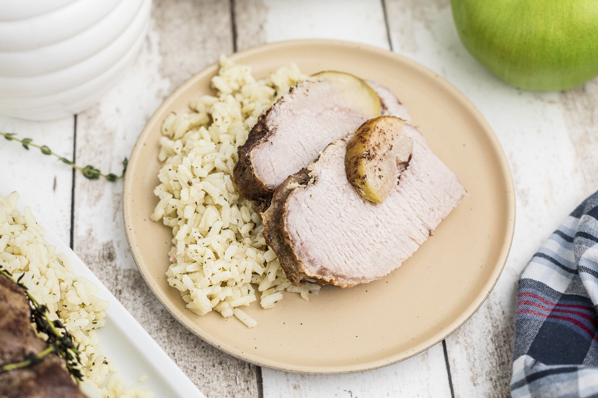 2 slices of honey apple pork loin on plate with rice.