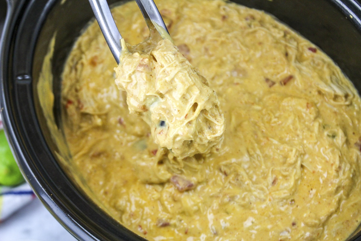 Tongs with queso chicken in them.