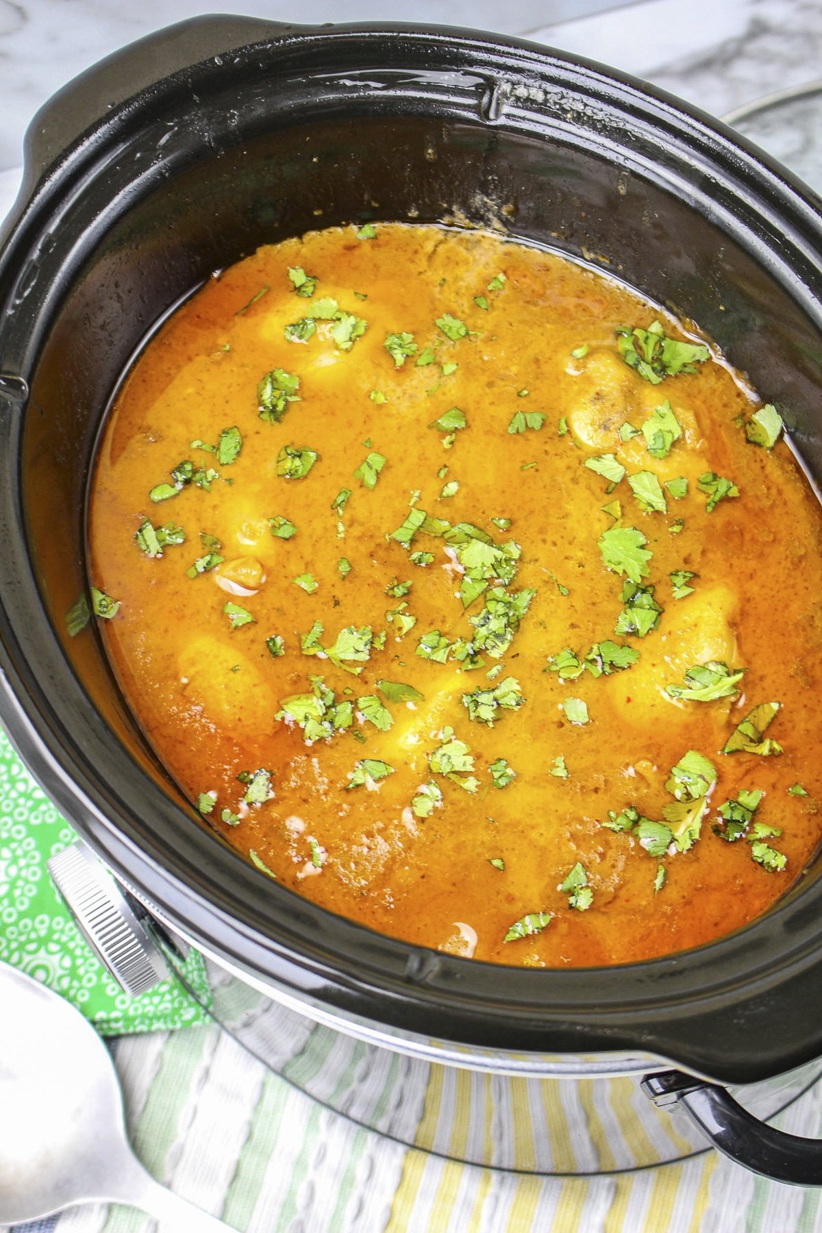 Thai peanut chicken in slow cooker with cilantro on top.