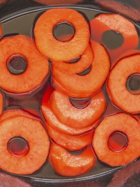 RIngs of apples in red hot sauce in crockpot.