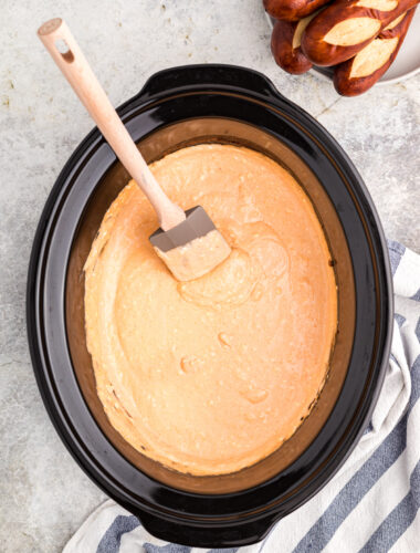 beer cheese dip with spatula in it, pretzels on side.