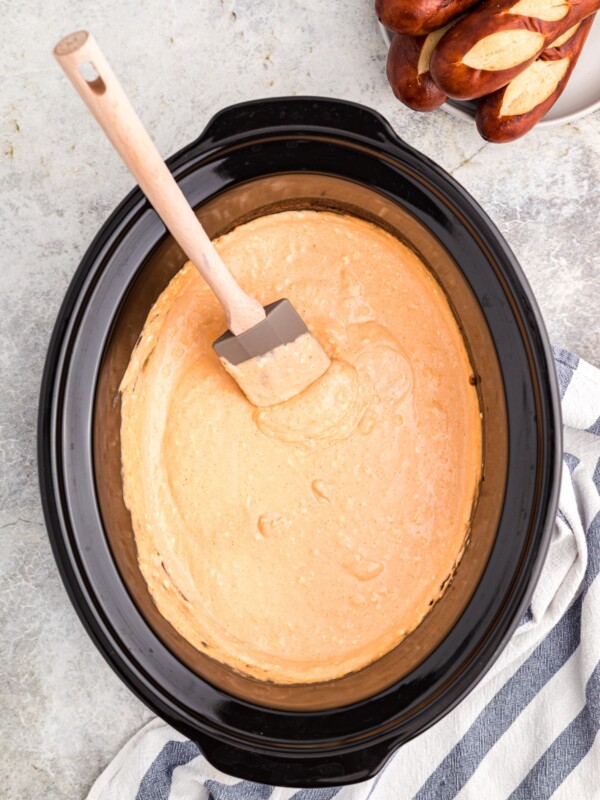 beer cheese dip with spatula in it, pretzels on side.
