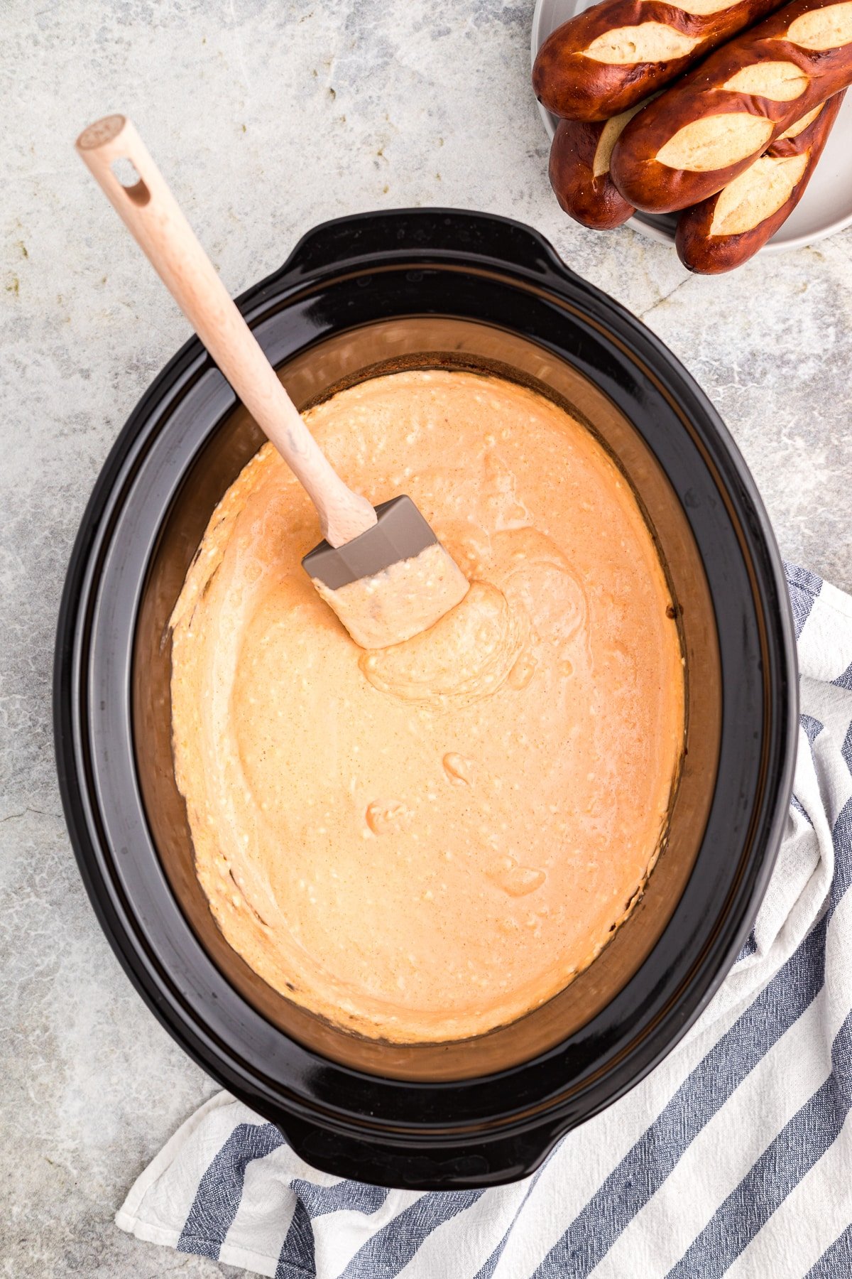 beer cheese dip with spatula in it, pretzels on side.