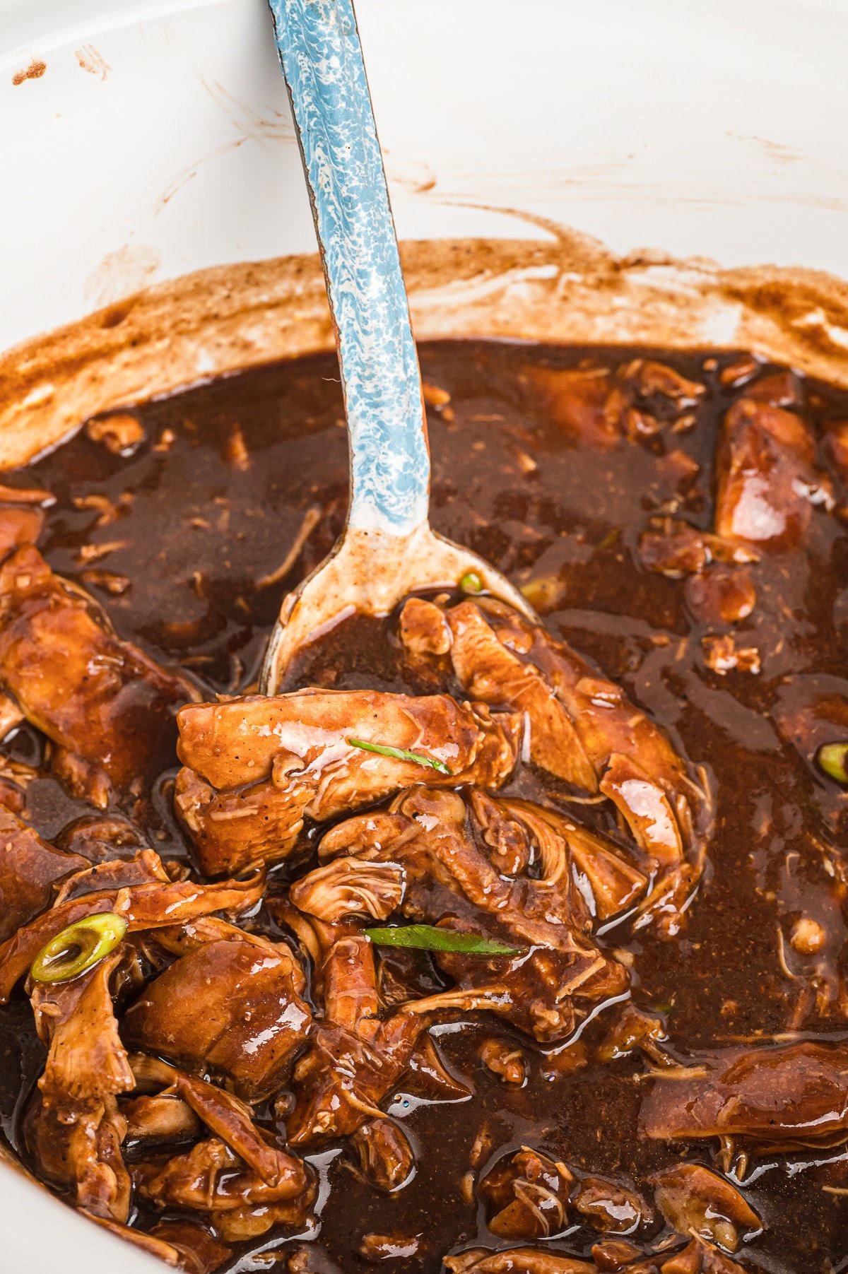 spoon in bourbon chicken in slow cooker.